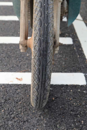 Close-up motorcycle wheels saw the wheels and tires on the reconstructed road - there was a warning xylophone ahead of the intersection and red light intersection.の写真素材