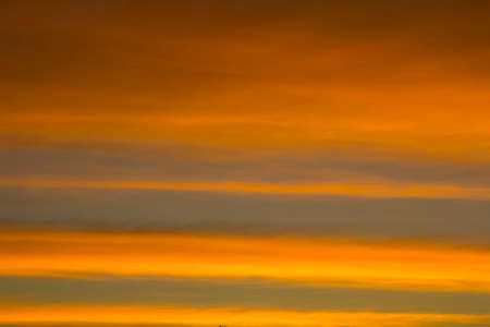 The sky is a horizontal line of yellow-orange and colorful colors in the beautiful evening in the midst of nature which is peaceful, warm and romantic in the countryside and is extremely beautiful.の写真素材