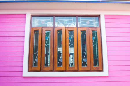 wooden windows and glass and the pink walls of the house are plasterwood that is popularly used to build houses these days. It is a modern style house and is becoming popular to replace the real wood.の写真素材