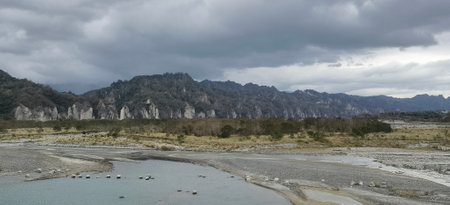 panoramic view of the river and mountains under cloudy sky.の写真素材