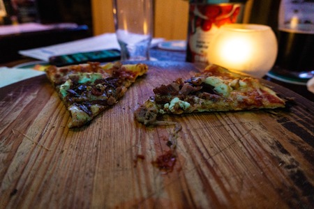 Sliced pizza and candle on wooden tableの写真素材
