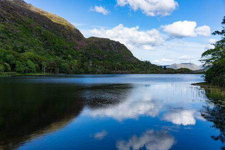 Lake landscape with mountain peaks covered in lush vegetation, Pollacapall Lough in, Connemara,...