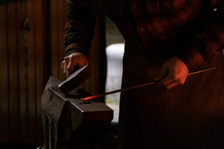 Blacksmith working on metal on anvil at forgeの写真素材
