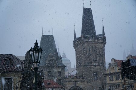 Prague castle towers e spires heading towards Charles bridge during a snowfallの写真素材