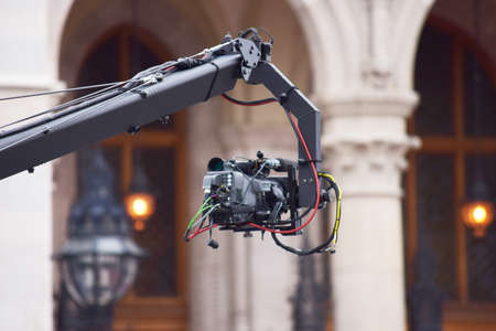 Video Camera is recording an event on a crane, front of a building in the morningの写真素材