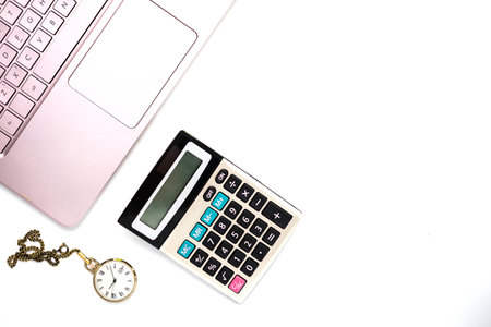 Laptop computer and calculatort on white office desk with gold pen and clock on white backgroundの写真素材