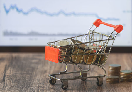 Coin in shopping cart with stock market board background, money for saving and invesment business...