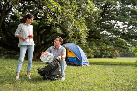 Volunteer lovers couple wearing gloves walking to to pick up garbage in the park To keep the environment cleanの写真素材