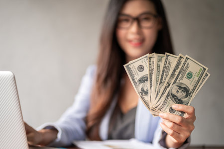 Dollar in a businesswoman hand. A Asia woman is working from home or office and glad to get dollar money from work and from a supplementary career or Part-time self-employment.の写真素材