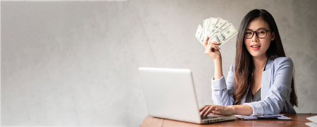 Dollar in a businesswoman hand. A Asia woman is working from home or office and glad to get dollar money from work and from a supplementary career or Part-time self-employment.の写真素材