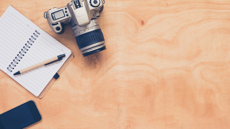 Top view of camera with notebook,pen and mobilephone on wooden table background.の写真素材