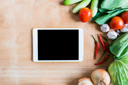 Top view of Fresh vegetables with tablet touch computer gadget on wooden table background.の写真素材