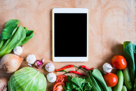 Top view of Fresh vegetables with tablet touch computer gadget on wooden table background.の写真素材