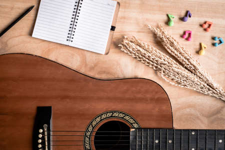 Top view of acoustic guitar with blank notebook on wooden table background.の写真素材
