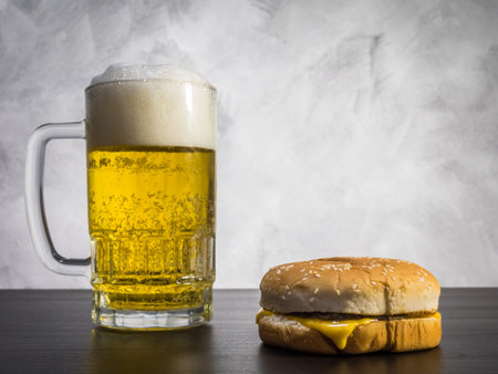 Hamburger with Glass of beer on the table over a grunge background.