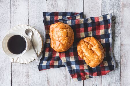 Top view of Coffee cup with bread and tablecloth on wooden table backgroundの写真素材