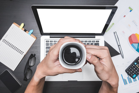 Top view of workplace with Laptop and document, Male hands holding a cup of coffee, Concepts for business analysis, financial report and strategy.の写真素材