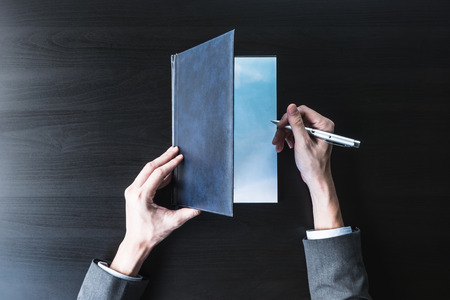 Top view of Businessman opening and  checking document on the black desk.の写真素材