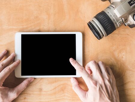 Top view of  male hands using tablet with camera on wooden table.の写真素材