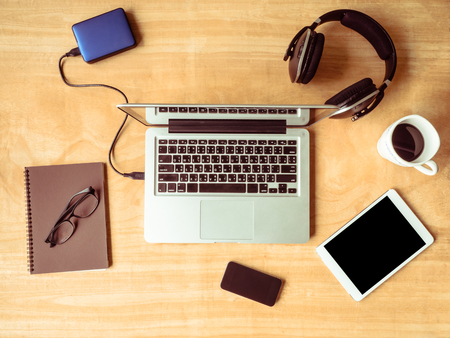 Top view of Electronic devices with notebook, glasses and coffee cup on wooden table background.の写真素材