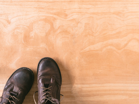 Brown leather men's boots on wooden table background, free space for textの写真素材
