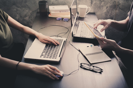 Coworkers working on the same desk, they are using a laptop with tablet, Start up business concept, Vintage toneの写真素材