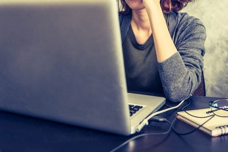 Close up of Casual young woman using a laptop on the desk. Vintage toneの写真素材
