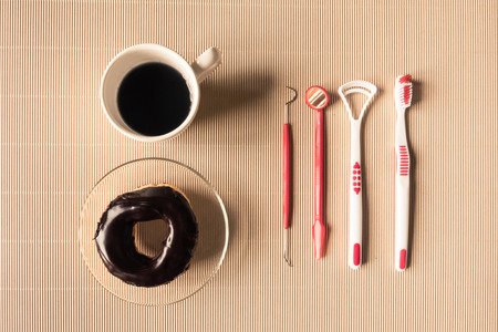 Top view of coffee cup with donut and dental tool equipment on table.の写真素材