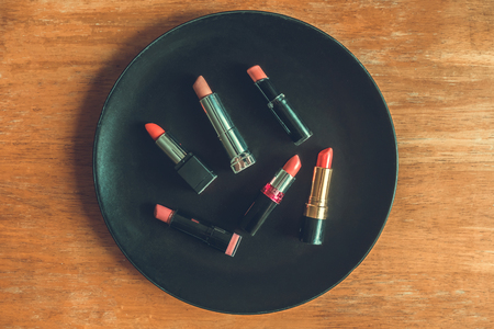 Top view of colorful lipsticks on the black plate over the wooden table. Makeup and Beauty conceptの写真素材