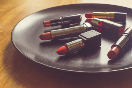 Colorful lipsticks on the black plate over the wooden table. Makeup and Beauty conceptの写真素材