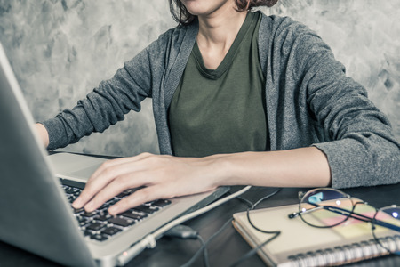 Close up of Casual young woman using a laptop on the desk.の写真素材