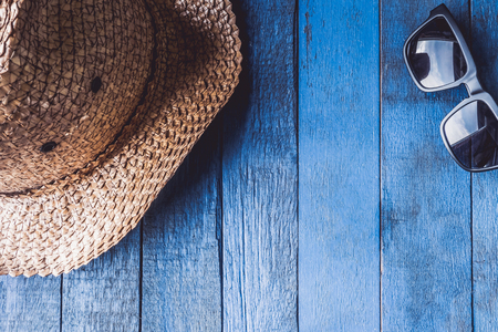 Hat with sunglasses on blue painted wood plank background.. Free space for textの写真素材