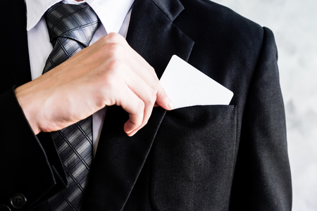 Close up of businessman putting white blank card into the pocket.の写真素材