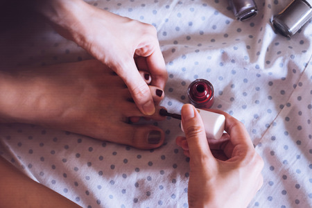 Close up of woman varnishing her toenails in the bedroom. Vintage toneの写真素材