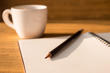 Blank notebook with pencil and coffee cup on wooden table background. Selective focusの写真素材