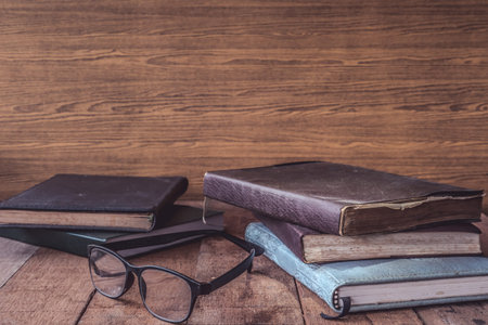Old books with glasses on wooden table. Free space for text