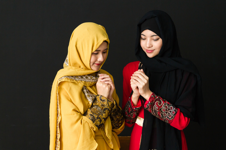 Portrait of Two beautiful young muslim women on a black background.の写真素材