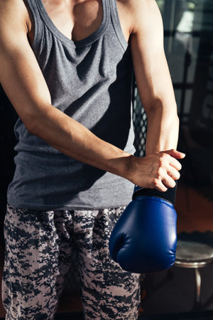 Young athletic man with boxing glove in fitness gym.
