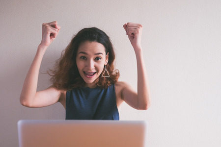 Happy young woman using a laptop on the desk.の写真素材