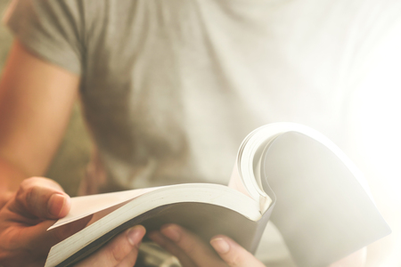Close up of male hands holding a book to read, Flare from the sunlightの写真素材