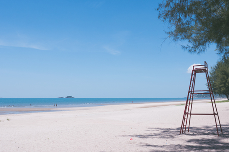 Beautiful beach with blue sky and a tall red lifeguard chair.の写真素材
