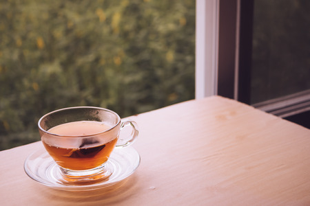 A cup of tea on the wooden table, tea bag in glass, nature background. Free space for textの写真素材