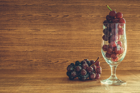 Red grapes in glass on the wooden table. Free space for textの写真素材