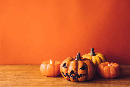 Halloween pumpkins with candlelight on an orange color background. Free space for text