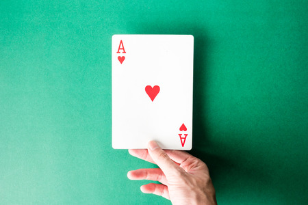 Hand holding a playing card on green background.の写真素材