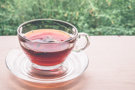 A cup of tea on the wooden table, tea bag in glass, nature background.の写真素材