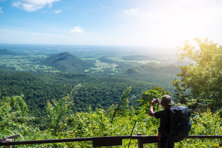 Man traveler taking picture on top of mountain with blue sky.の写真素材
