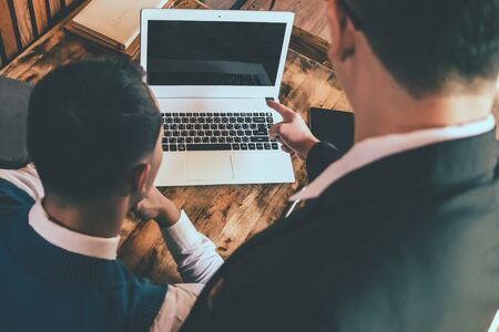 Two business men working on a laptop. senior and junior businessman discuss something during their meeting.の写真素材
