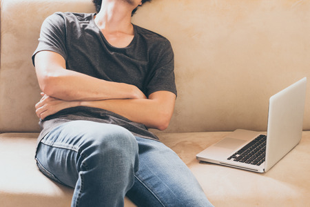 Close up of young man sleeping on the sofa at home with laptop.の写真素材