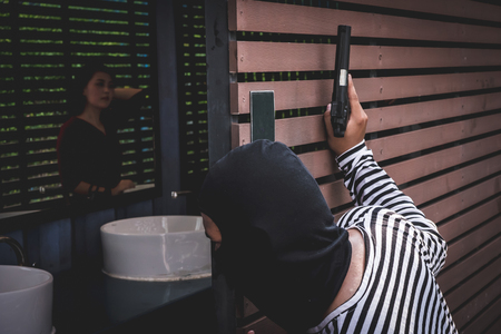 Thief is looking at an asian woman who is in a toilet alone because he want to steal her bag.の写真素材